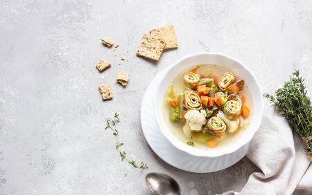 Vegetable soup with egg pancakes on light gray background. Traditional German Flaedlesuppe and Austrian Frittatensuppe.の写真素材
