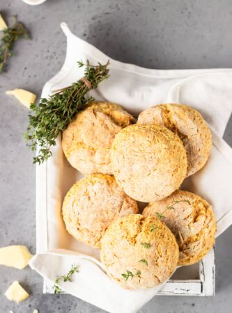 Freshly baked delicious homemade English scones with cheese and thyme on a light gray wooden tray. Gray stone background.の写真素材