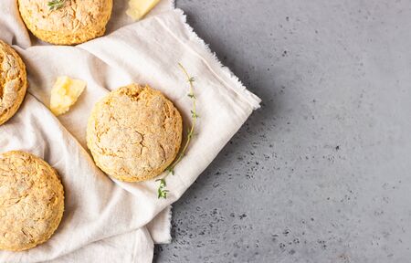 Cheese scones, pieces of cheese and thyme on a gray napkin. Gray stone background, toned image.