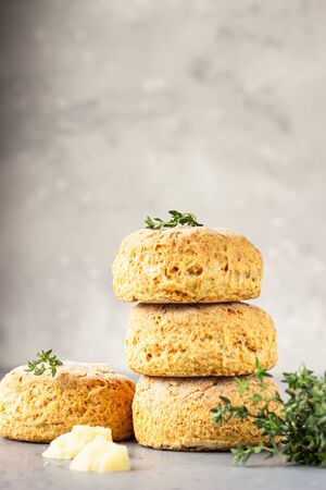 Homemade English scones or buttermilk biscuits with cheese, thyme and pieces of cheese, gray concrete background.の写真素材