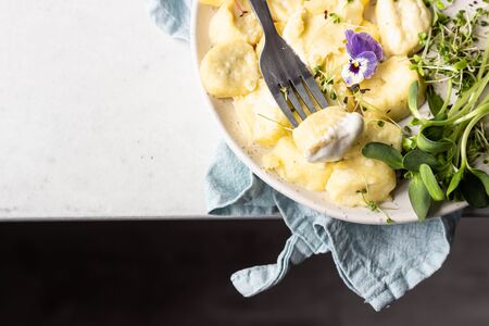 Curd and cheese dumplings served with microgreens and sour cream on a ceramic plate. Traditional Ukrainian or Russian lazy dumplings (vareniki). Healthy breakfast.の写真素材