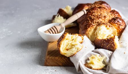Homemade challah bread on a wooden cutting board over light gray stone background. Shabbat, hebraism traditional bread.の写真素材