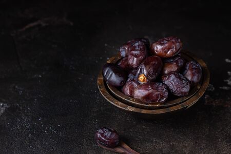Juicy organic medjool dates on dark brown concrete background. Copy space, selective focus.の写真素材