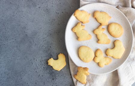 Easter cookies on a ceramic plate with napkin, gray stone background. Homemade butter and sugar...