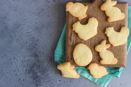 Easter cookies on a wooden cutting board with milk, gray stone background. Homemade butter and sugar...