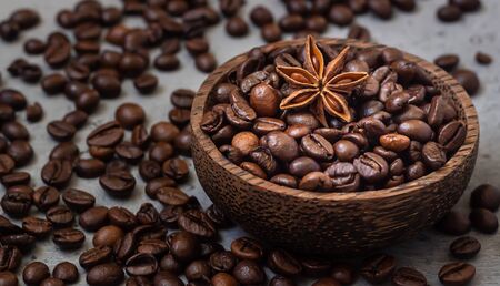 Wooden bowl with roasted coffee beans with star anise, gray stone background.の写真素材