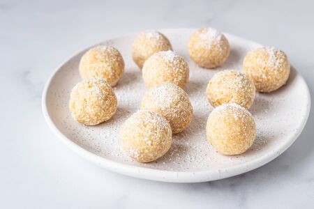 Traditional Indian festival sweets (Laddoo or Laddu) with coconut flakes on a ceramic plate, light...