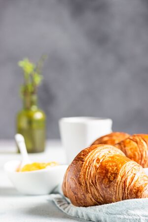 Fresh croissants on a gray linen napkin with jam and coffee. Light gray concrete background.の写真素材