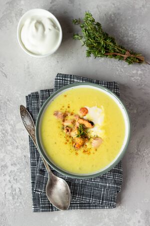 Thick milky chowder soup with seafood served with sour cream, thyme and pepper. Light gray stone background.の写真素材