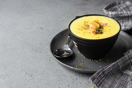 Bowl with thick clam chowder, decorated with seafood, thyme and pepper. Gray stone background.