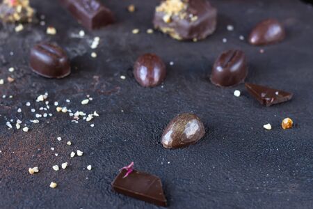 Assortment of sweet confectionery with chocolate candies and pralines on a dark brown stone...