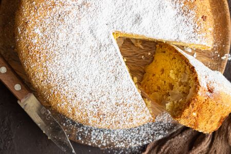 Homemade delicious sponge or soft cake on a dark brown concrete background. Freshly baked Sharlotka,...