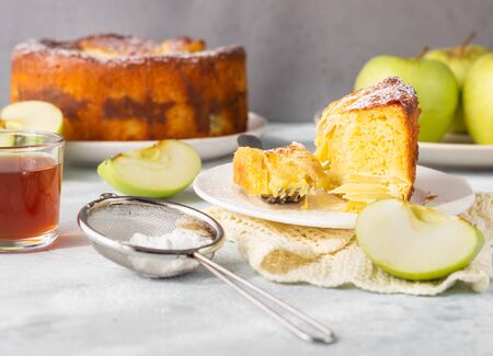 Piece of charlotte with apples. Delicious apple pie or sponge cake decorated with powdered sugar. Morning atmospheric lighting, trendy soft shadows, selective focus.の写真素材