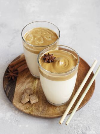 Iced Dalgona coffee in tall glass with spices. A trendy fluffy creamy whipped coffee. Korean coffee drink. Light gray concrete background.の写真素材