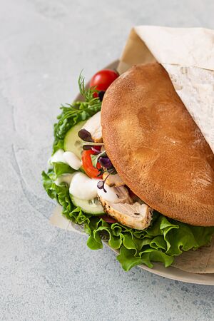 Pita bread sandwich with fresh vegetables and roasted chicken. Healthy snack. Takeaway food, street fast food.の写真素材