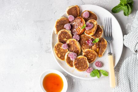 Mini pancakes with raspberries, mint and jam for breakfast on a ceramic plate. Pancakes cooked for breakfast in the home kitchen.の写真素材