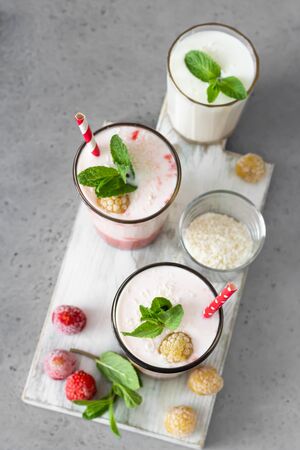 Layered strawberry and raspberry smoothie or milkshake in glasses decorated with mint, raspberry and coconut flakes. Healthy food for breakfast or snack.の写真素材