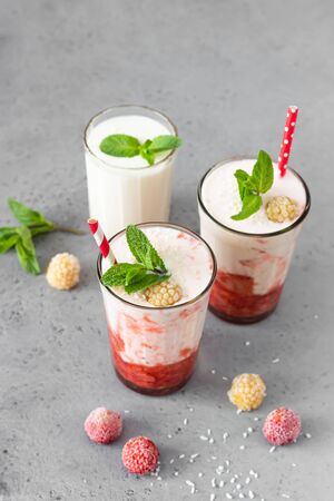 Layered strawberry and raspberry smoothie or milkshake in glasses decorated with mint, raspberry and coconut flakes. Healthy food for breakfast or snack.の写真素材