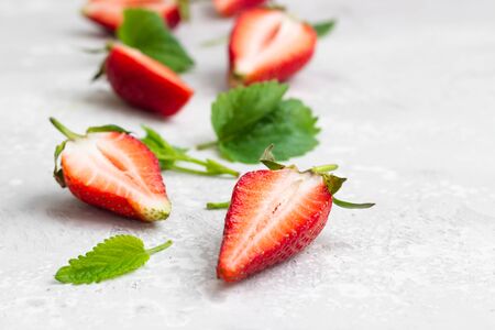 Composition with whole and sliced strawberries and mint leaves on a grey background. Close up.の写真素材