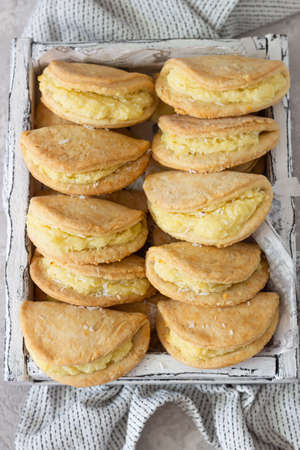 Homemade buns or pastries with cottage cheese on a wooden tray, light gray stone background....