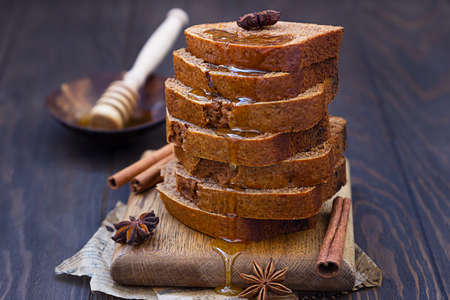 Gingerbread and honey loaf cake with cinnamon and anise on wooden background.