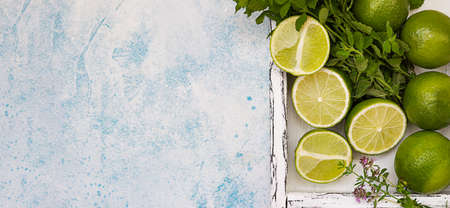 Lime and mint on light wooden tray, blue background. Summer concept. Top view.の写真素材