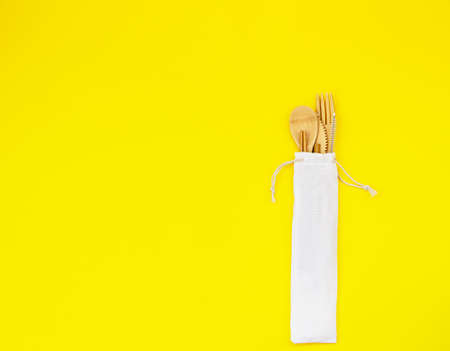 Eco-friendly disposable utensils made of bamboo wood on yellow background. Zero waste concept. Top...