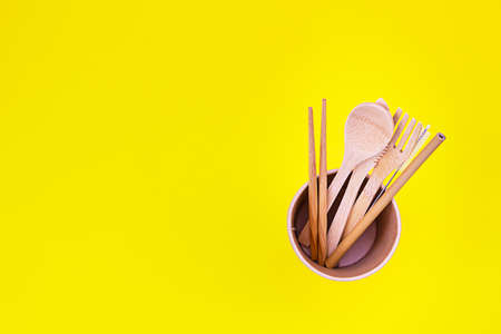 Eco-friendly disposable utensils made of bamboo wood on yellow background. Zero waste concept. Top view.の写真素材