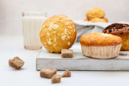Vanilla muffins and muffins with streusel in paper cups with a glass of milk on light background. Breakfast or snack for children.の写真素材