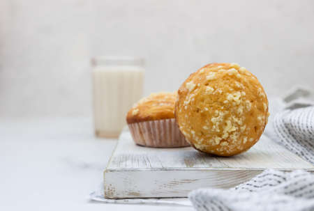 Vanilla muffins and muffins with streusel in paper cups with a glass of milk on light background. Breakfast or snack for children.の写真素材