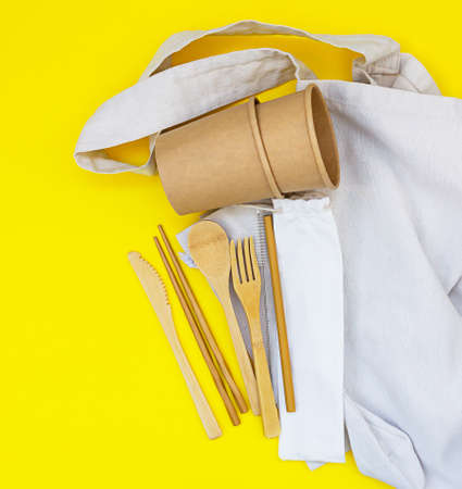 Eco friendly bamboo cutlery, eco canvas bag and reusable cup for soup or noodles on yellow background. Zero waste flatware concept. Plastic free. Top view.の写真素材