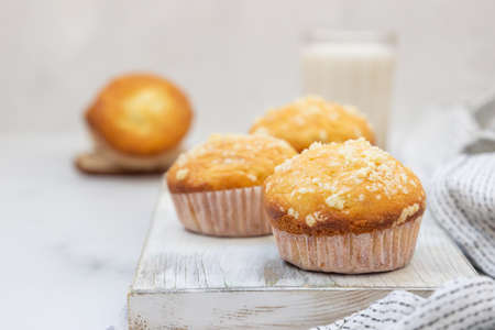Vanilla muffins and muffins with streusel in paper cups with a glass of milk. Breakfast or snack for...