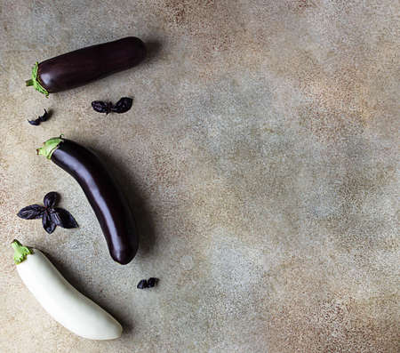 Fresh delicious white and purple eggplants with purple basil on concrete background. Top view.の写真素材