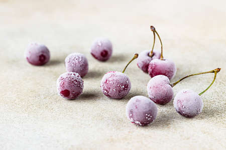 Frozen sweet black cherries covered with hoarfrost on stone background. Summer food. Useful, proper nutrition.の写真素材