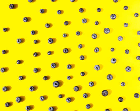 Flat lay composition with blueberries on yellow background. Berries pattern, minimal composition....