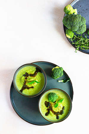 Delicious broccoli cream soup served with spicy oil and mint. Vegetarian dish. Top view. Concrete background.の写真素材