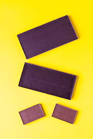 Dark and milk chocolate on pastel yellow background. Top view.