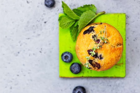 Fresh homemade delicious blueberry muffins decorated with thyme, fresh berries and mint on gray concrete background.の写真素材