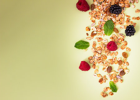 Flat lay composition with muesli or granola in jar with raspberries, blackberries and mint on green...