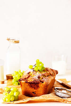 Delicious homemade grape loaf cake with thyme and sugar powder on parchment paper. Light stone...
