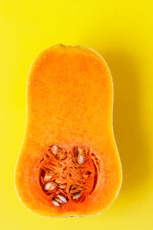 Two halves of butternut squash on yellow background. Seasonal, harvest, fall, organic food, dieting,...