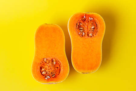 Two halves of butternut squash on yellow background. Seasonal, harvest, fall, organic food, dieting,...