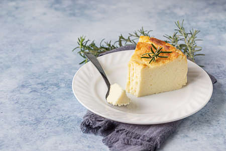 Lemon vanilla cheesecake decorated with rosemary, mint and lemon slices. Ricotta no crust cheesecake or casserole. Blue concrete background.の写真素材