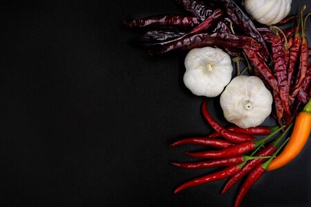 Dried red chilli pepper and fresh red, orange chilli pepper with garlic on black floor top view close upの写真素材