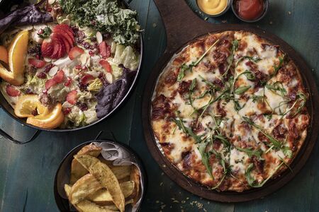 Delicious pizza with salad and friesの写真素材