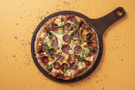 salami pizza in yellow top viewの写真素材
