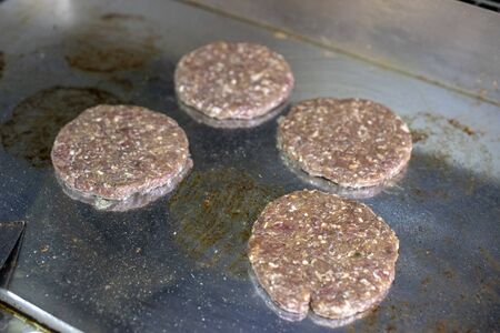 Grilling hamburger meat on boardの写真素材