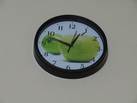 Green apple on the wall clock showing 5 o'clock in the morning