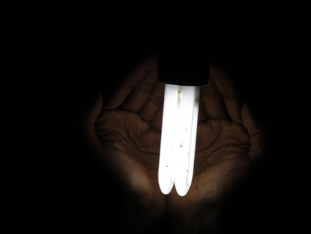 Light bulb in the hands of a man on a black background.