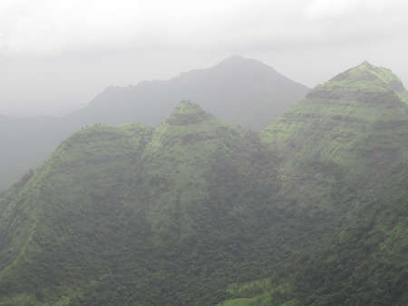 Aerial view of green mountains in the fog. Nature background.